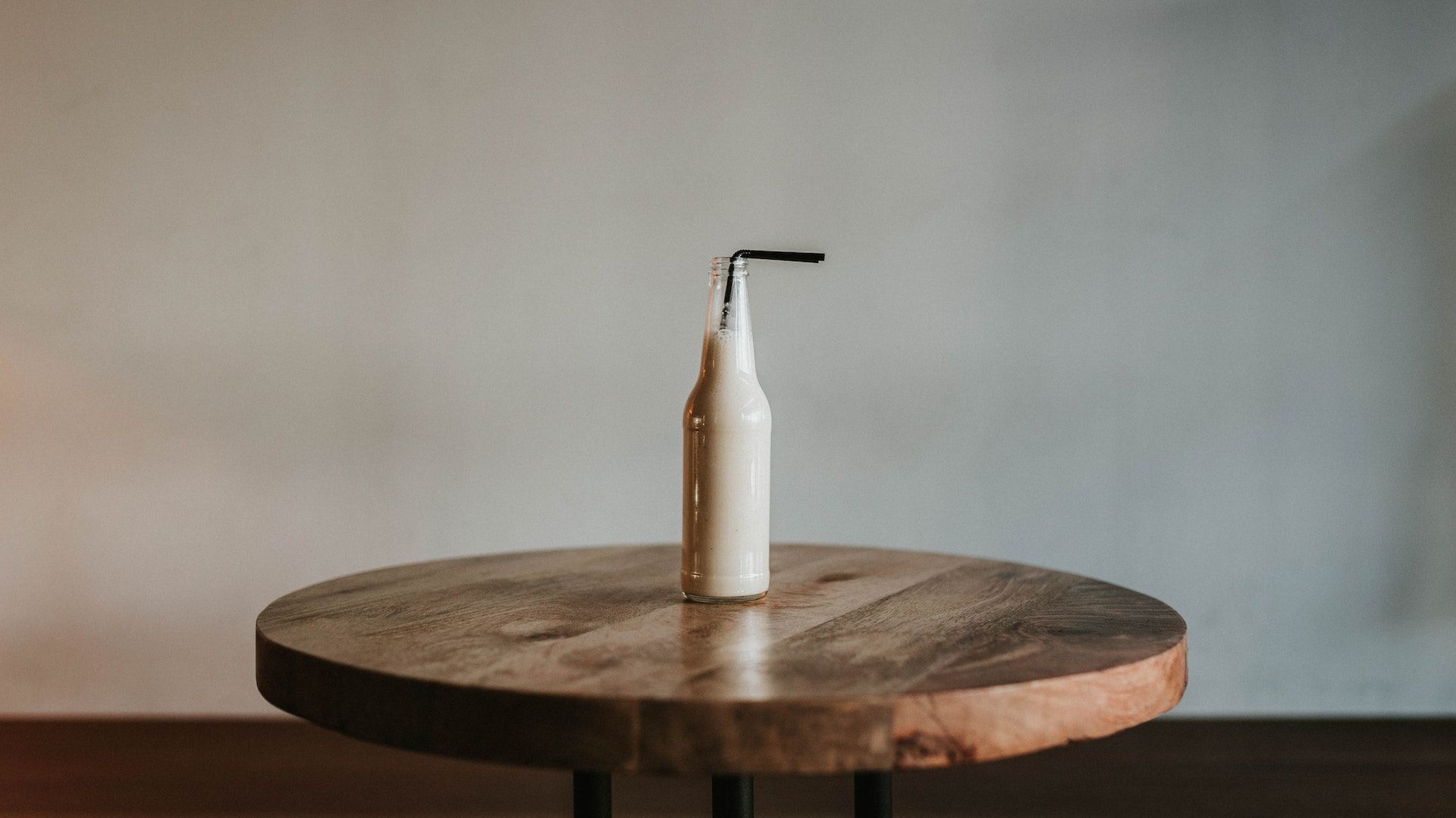 Glass Bottle Filled With Black Straw on Brown Wooden Table